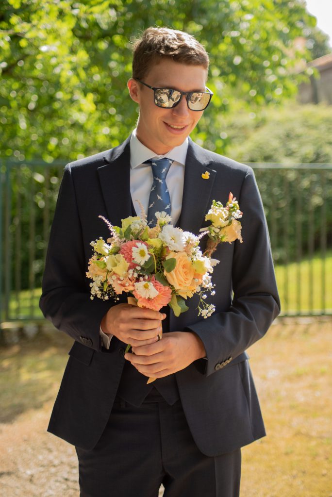Marié souriant avec le bouquet de la mariée pendant leur mariage laïque à Montrevault-sur-Èvre, dans le Maine-et-Loire.