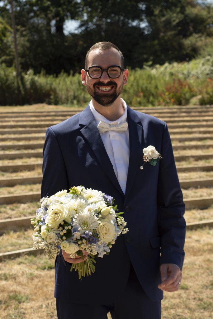 Marié souriant avec le bouquet de la mariée pendant leur mariage civil à Montfaucon-Montigné, dans le Maine-et-Loire.